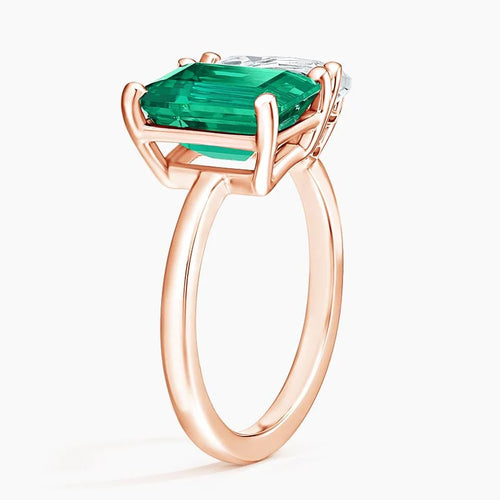 Close-up of rose gold moissanite and emerald gemstone ring